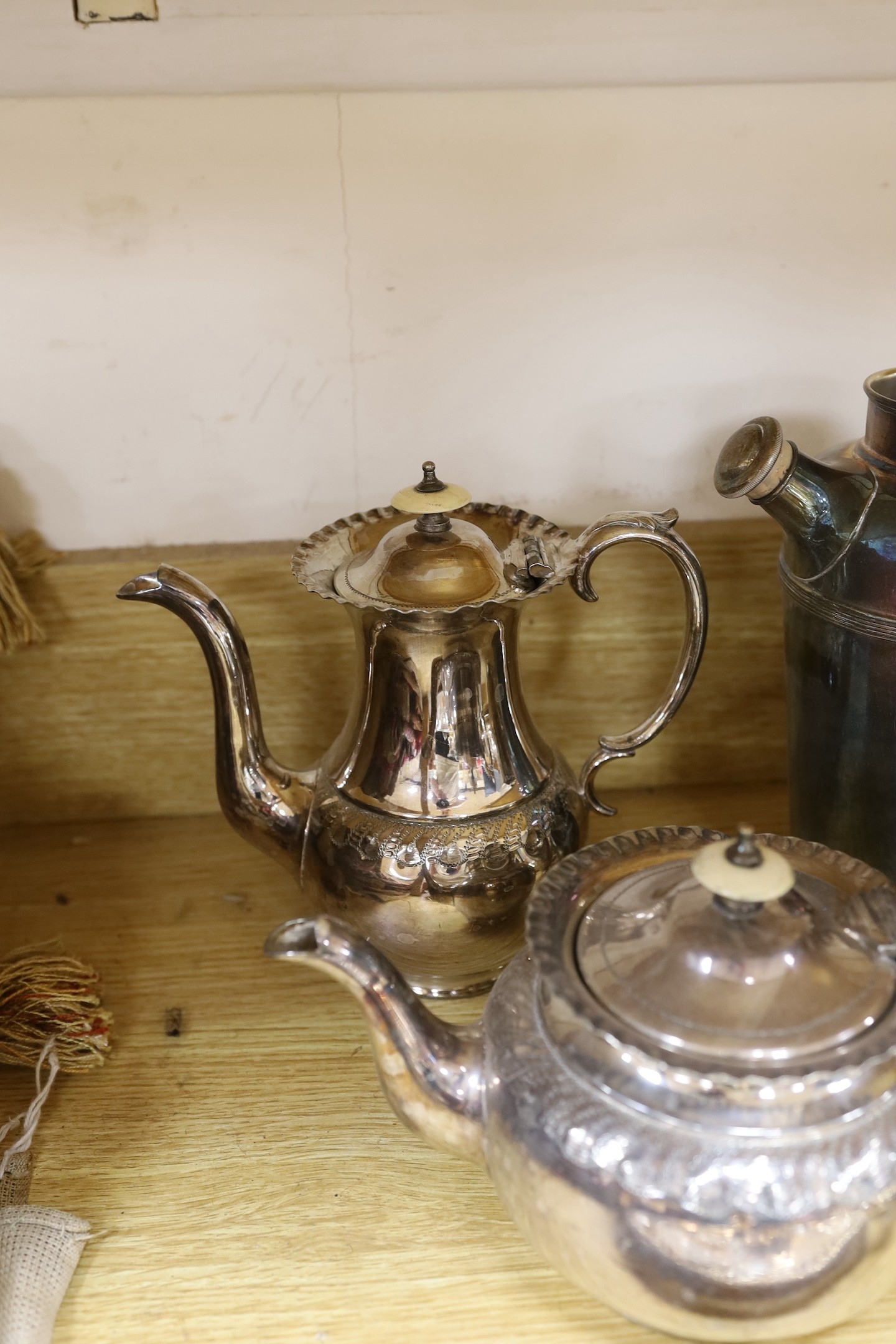 A quantity of assorted plated wares including a chamberstick, a tea set, flatware, a cocktail shaker, a sauceboat, goblets, etc.